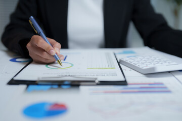 Businesswoman analyzing financial charts and using calculator, focusing on investment and financial planning strategies for sustainable development and future growth