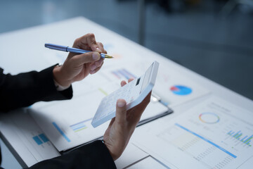 Businesswoman using calculator and analyzing financial data in office meeting, working with charts and graphs, planning budget and investment strategy