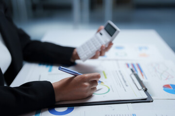 Fototapeta premium Businesswoman working diligently at her desk, analyzing financial documents and calculating figures with a calculator, focusing on business analysis and accounting strategies