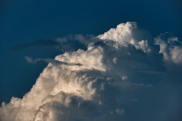Na tle błękitnego nieba widoczna górna część skłębionej białej chmury cumulunimbus, często przynoszącej burze i intensywne opady deszczu.