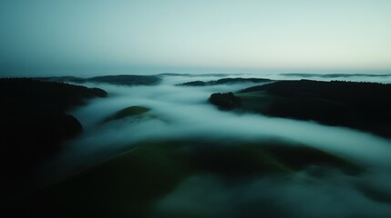Fog envelops lush green lands in abstract aerial view at dawn