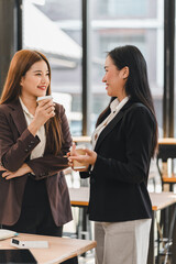 Two businesswomen talking and smiling in modern office