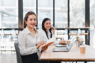 Smiling women in office with headsets and laptops