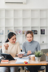 Obraz premium Two women discussing work at desk with documents and devices