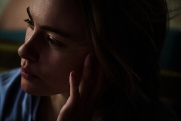 Close up portrait of beautiful blonde girl in real life in dark lighting deep shadows