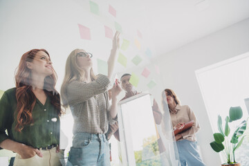 Photo of all business team members concentrated searching solution put stickers on glass indoors...