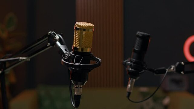 No people shot of modern podcasting studio with acoustic panels, two professional microphones for podcast recording, ring light in blurred background