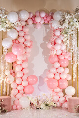 Photo zone for wedding receptions, or festive zone for celebrating girl's birthday party. Arch decorated with pink and white balloons, flowers. Photo wall decoration space or place for text.