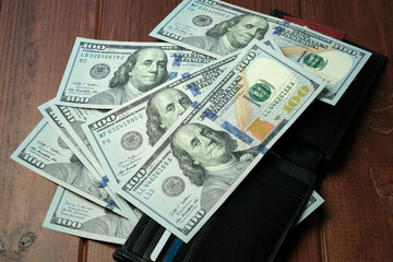 Stacks of hundred dollar bills resting on a wooden table in a quiet setting