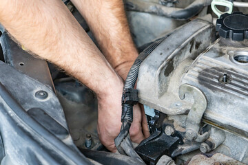 Male hands repairing a car. Replacing parts near a car engine. Automobile mechanic hands repairs car.