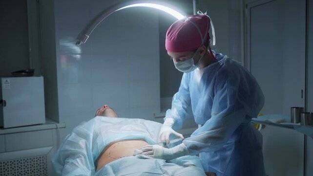 A medical professional in surgical attire is seen focusing on an abdominal procedure in a well-lit operating room. The surgeon skillfully prepares the area for incision.