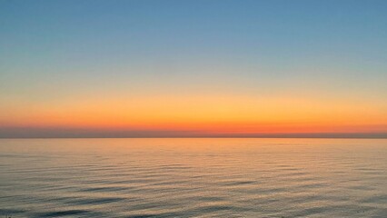 A breathtaking scene of the sun setting over the sea, casting vibrant hues of orange, pink, and blue across the sky while its reflection shimmers on the calm water
