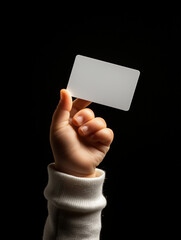 Mão de criança segurando um cartão branco em fundo preto – Conceito de pagamento, cartão em branco personalizável, finanças ou identificação.