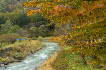 Beautiful view of Hakuba Village with the Japan Alps as a backdrop and a clear stream flowing through it in autumn, view from Oide Park, Nagano Prefecture, Japan 