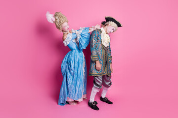 Elegant couple in baroque costumes posing against a vivid pink background, embodying vintage...