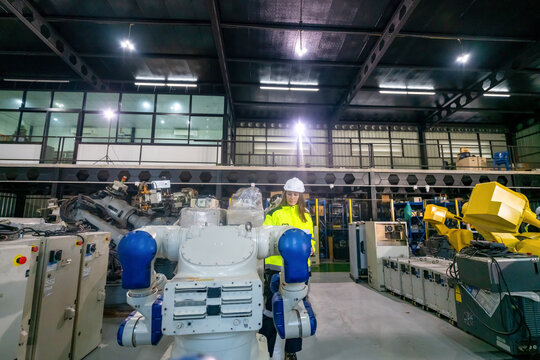 Engineer Interacts With Robotic Arm in Modern Industrial Facility During Daytime