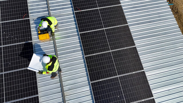 Workers Install Solar Panels on Commercial Building Rooftop for Renewable Energy