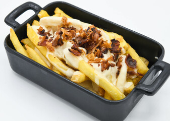 Patatas fritas con cebollas fritas y tocino en un plato negro sobre un fondo blanco