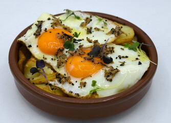 Huevos fritos con patatas sobre fondo blanco