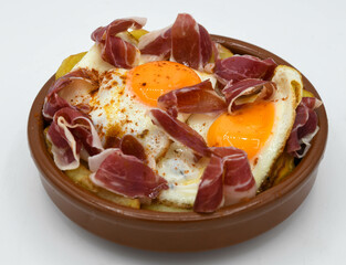 Huevos fritos con patatas y jamón curado sobre fondo blanco