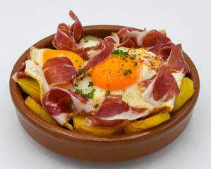 Huevos fritos con patatas y jamón curado sobre fondo blanco