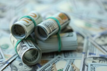 Many rolls of one hundred dollar bills lies on big amount of american currency banknotes