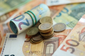 Roll of euro currency money bills and many euro cents on banknotes of european union