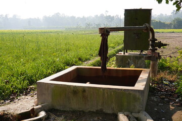 A groundwater extraction system, likely a hand pump connected to a well or tubewell in the agricultural field 