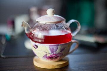 a teapot with tea on a desk with a blurred background