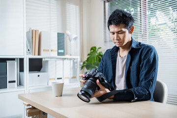 Man examining camera at desk in bright office setting