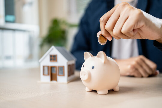 person saving money with piggy bank and house model