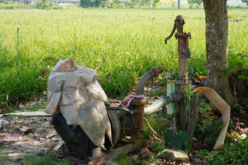 A manual water pump, commonly used in rural areas for accessing groundwater which is a simple machine that uses a hand-operated lever to draw water from a well