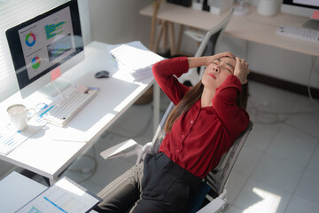 Young professional woman feeling tired and suffering from headache, burnout and overwork in office,...
