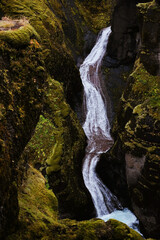 waterfall surrounded by mossy Icelandic cliffs