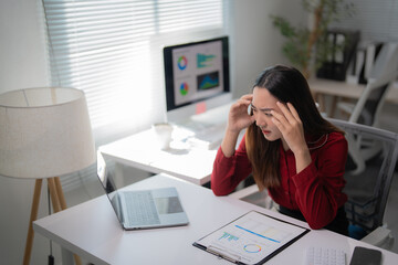 Young professional suffering from headache and stress while analyzing financial reports and using...