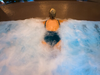 A girl enjoys the massage jets in a pool.