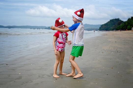 kids in Santa hat on the beach - Powered by Adobe