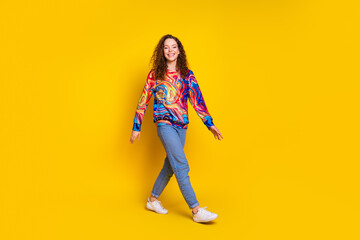 Young woman in vibrant casual style outfit walking confidently on bright yellow background