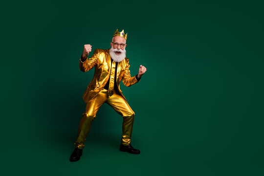 Charismatic senior man in a glowing golden suit celebrates with confidence on a green background