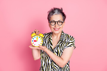 Portrait of pretty aged lady hold bell ring clock wear zebra print shirt isolated on pink color background