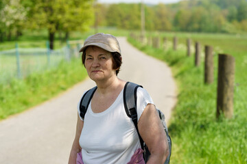 Fototapeta premium Mature woman with a backpack on a country road in springtime