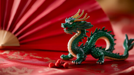 Obraz premium Decorative green dragon figurine sits on red fabric with a fan and traditional motifs during a festive celebration