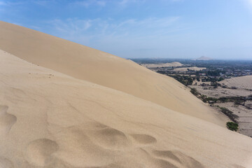 View of the city of Ica surrounded by towering sand dunes in the Peruvian desert landscape