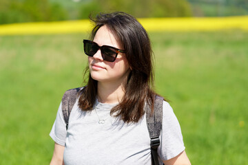 Portrait of a beautiful young woman with backpack and sunglasses in the countryside