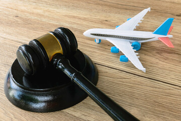 Legal and Aviation Concept: Judge's Gavel and Toy Airplane on Wooden Surface.