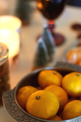 Various Christmas decorations, cookies, chocolate, nuts and tangerines, wine glasses and lit candles on the table. Holiday hygge at home. Selective focus.
