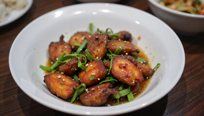Delicious fried fish balls served in sauce with green onions in a white bowl