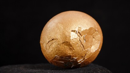 Close-Up of a Cracked Golden Egg with a Dark Background.