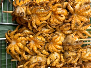 A heaping pile of deliciously fried octopus skewers cooking on a grill