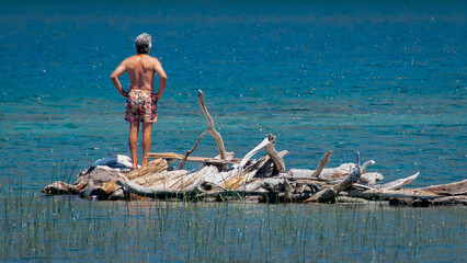 Adult man with summer short standing in the middle of lake, bariloche, rio negro province, argentina